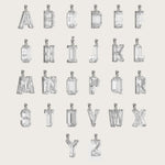 Collection of silver alphabet pendants, each adorned with sparkling gemstones, displayed on a light beige background.