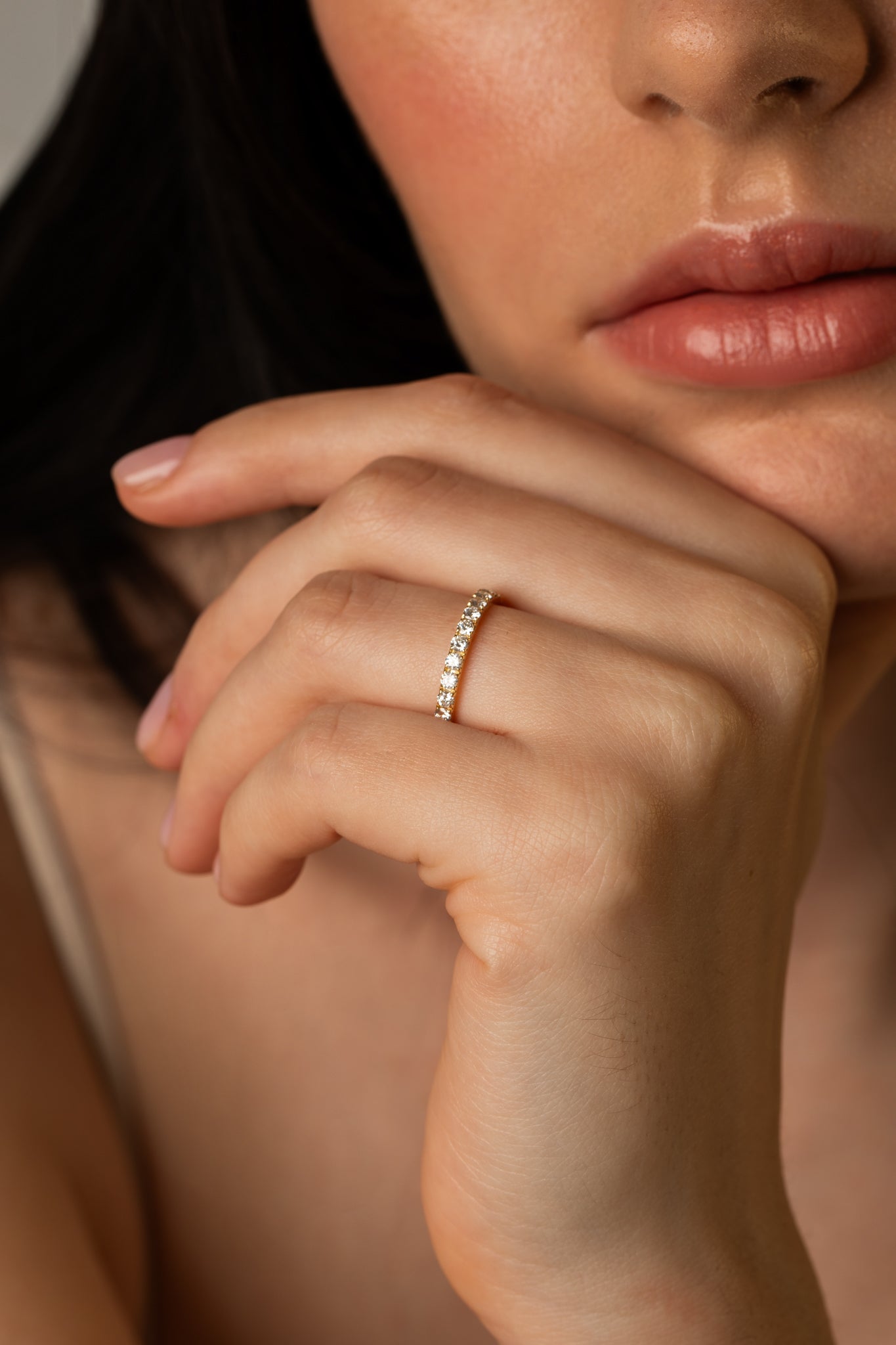 A close-up lifestyle shot focusing on a model resting her hand near her face, beautifully showcasing the bold silhouette of the Pavé Diamond Ring III in 18k yellow gold.