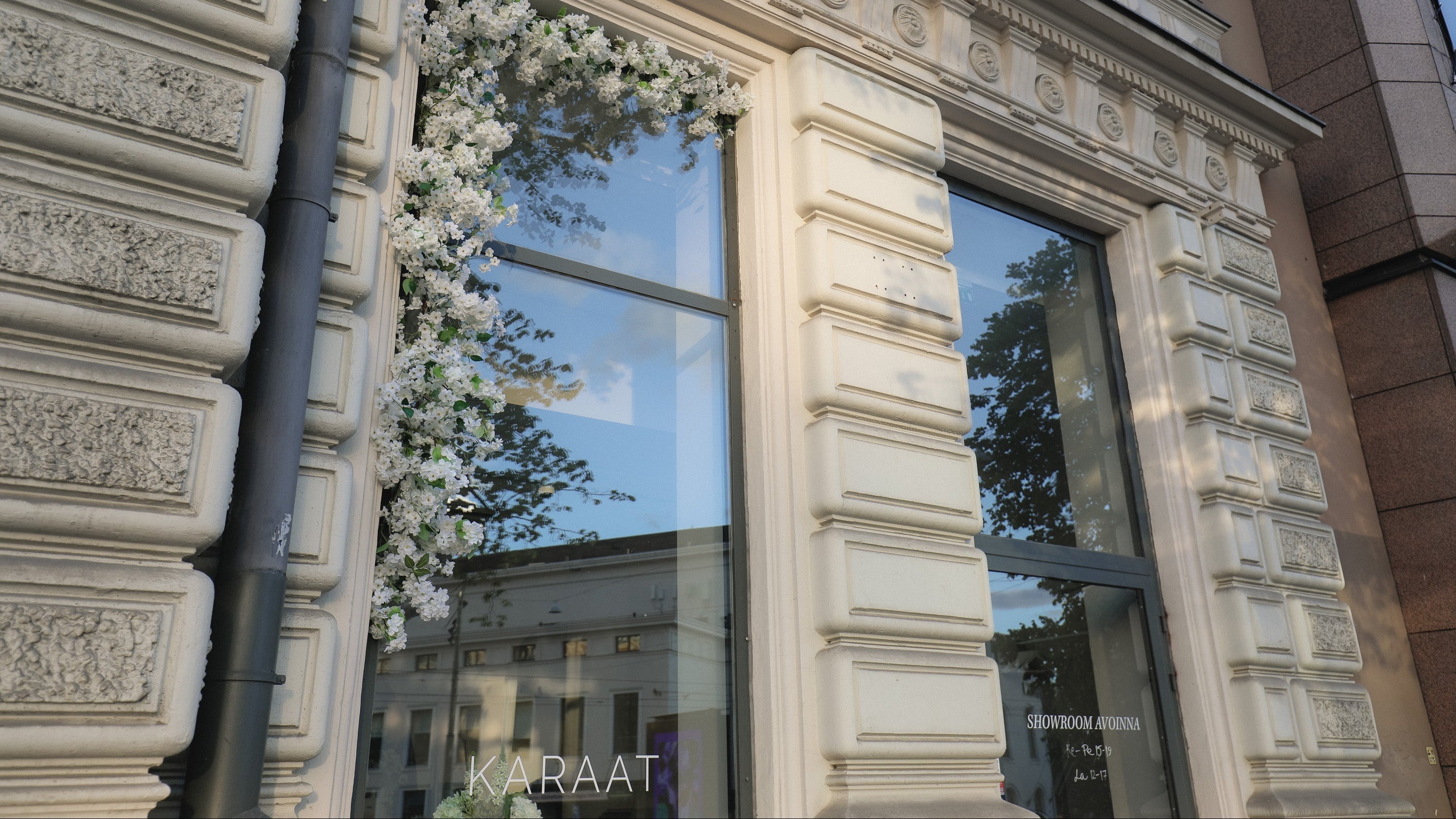 Decorative floral arrangement in a window of a building with 'Karaat' branding.
