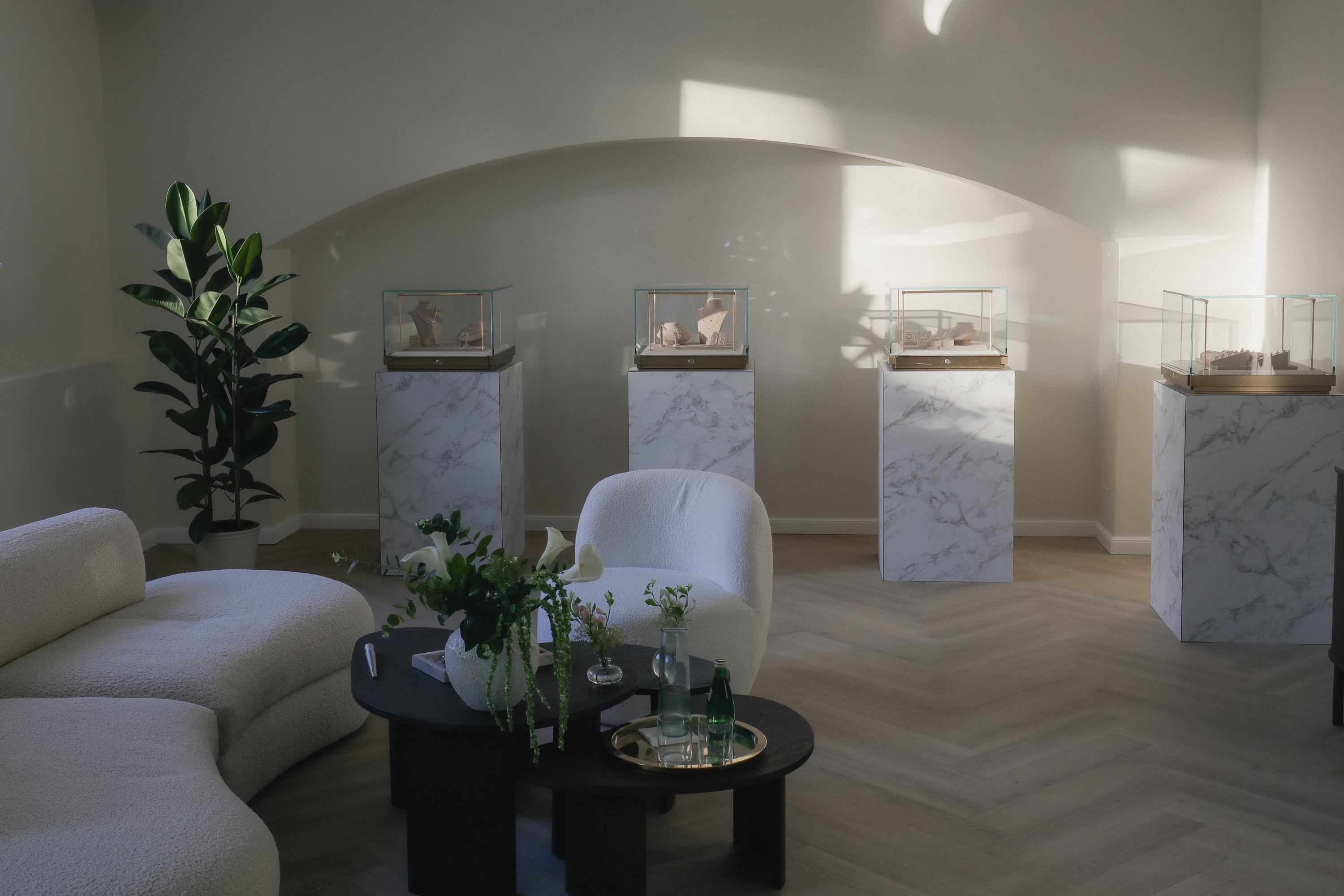 Modern fine jewelry brand showroom with white furniture, a coffee table, and decorative elements.