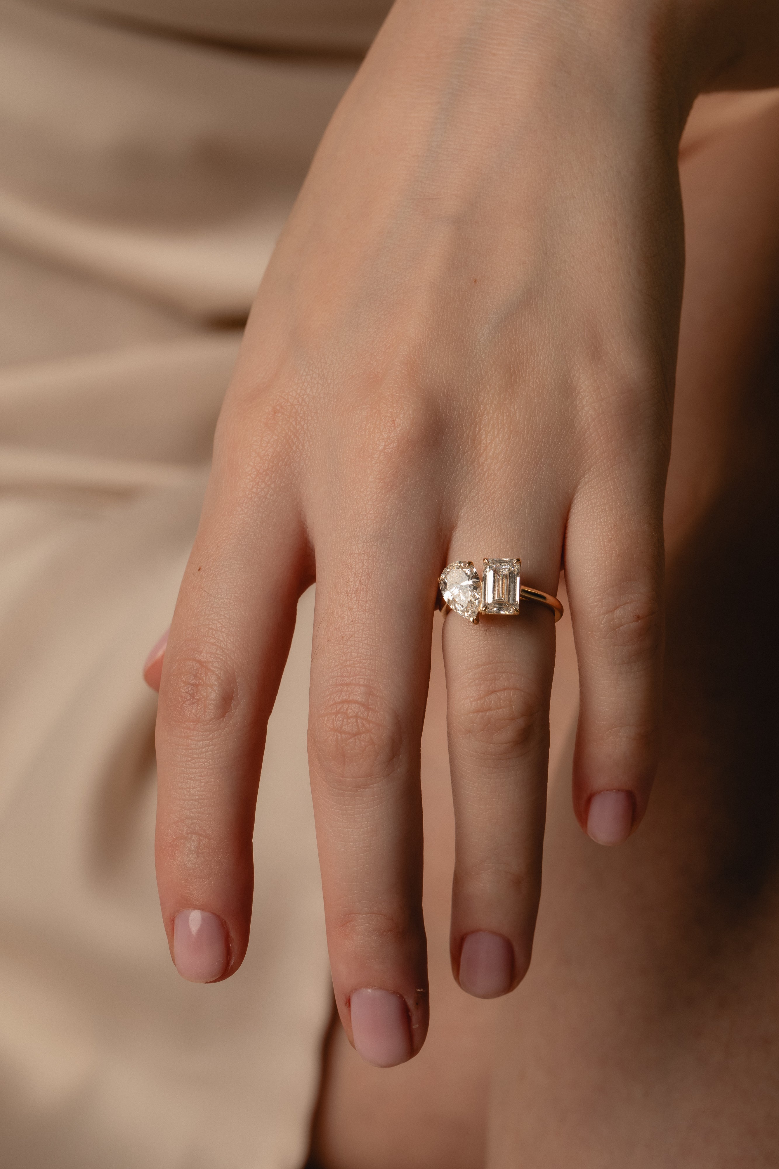 Emerald and Pear Toi et Moi two-stone diamond ring in yellow gold on a model's hand, top view
