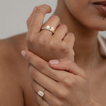 A beautiful shot of a model's crossed hands, styled with a white gold KARAAT emerald-cut solitaire ring on her ring finger and a bold ring stack on her index finger.