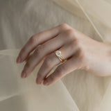 A KARAAT Emerald Trilogy diamond engagement ring in 18k yellow gold styled with a delicate organza dress.