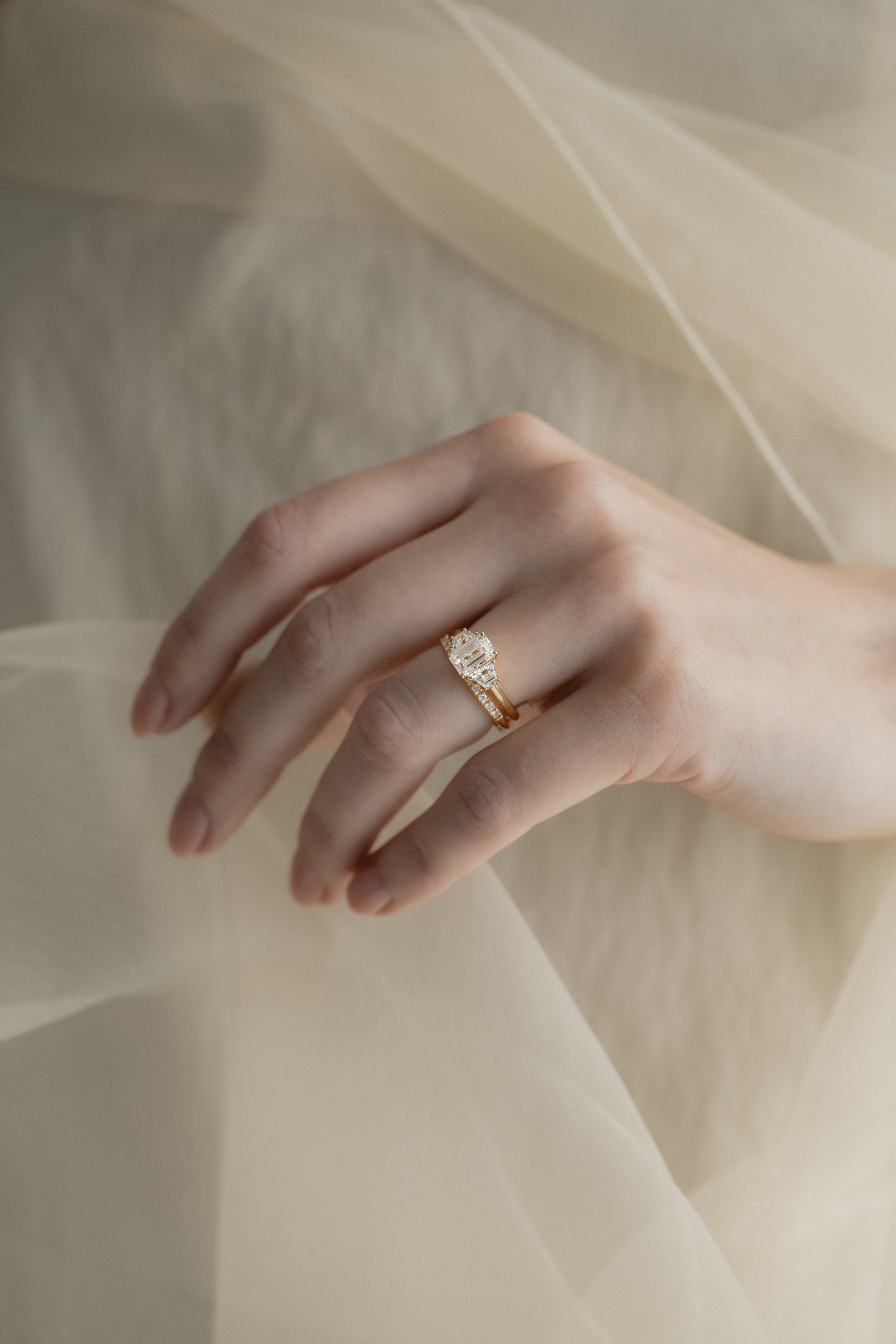 A KARAAT Emerald Trilogy diamond engagement ring in 18k rose gold styled with a delicate organza dress.
