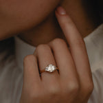 Detailed view of the KARAAT Emerald Trilogy in 18k yellow gold on a model's hand, highlighting the elongating emerald cut.