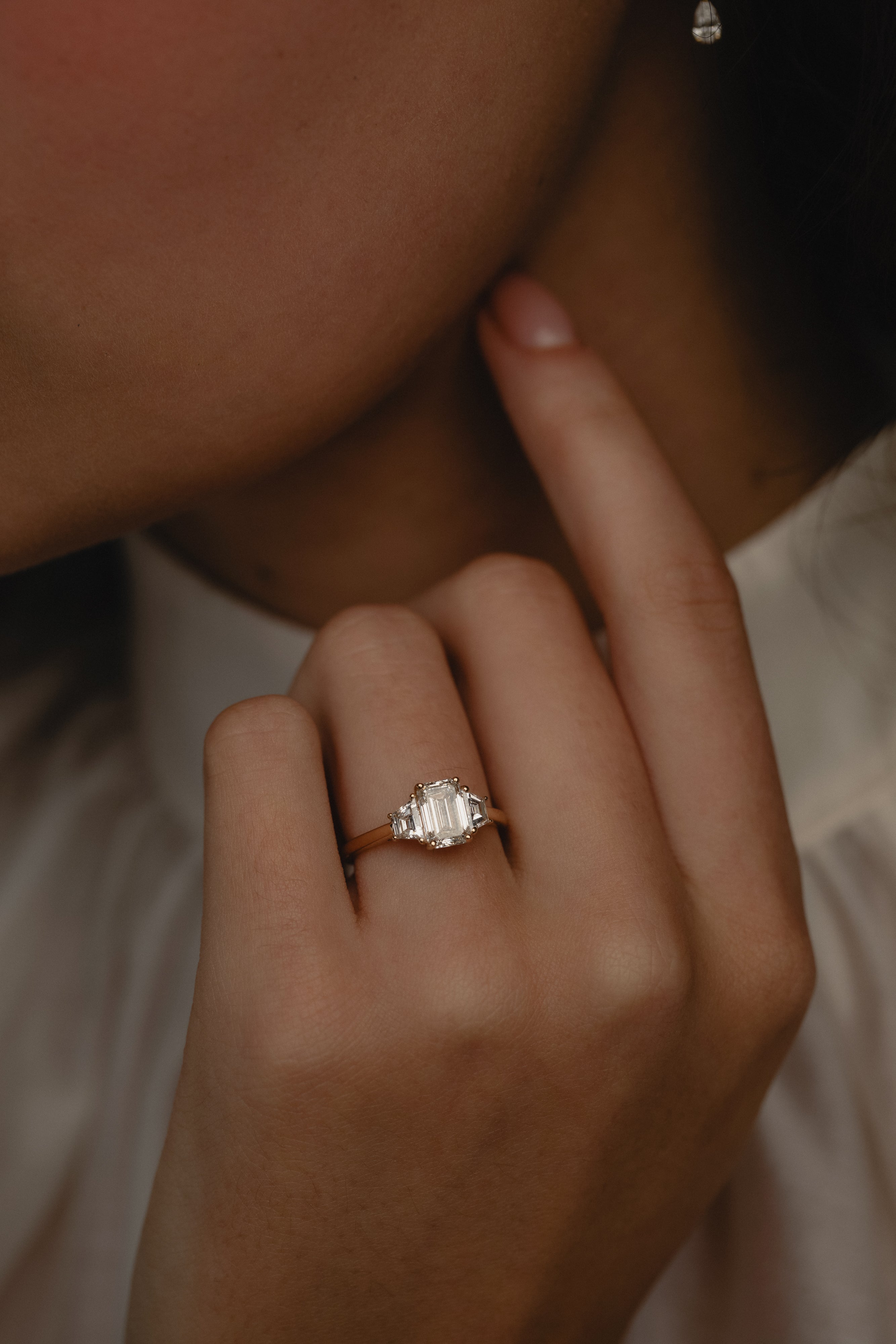 Detailed view of the KARAAT Emerald Trilogy in 18k yellow gold on a model's hand, highlighting the elongating emerald cut.