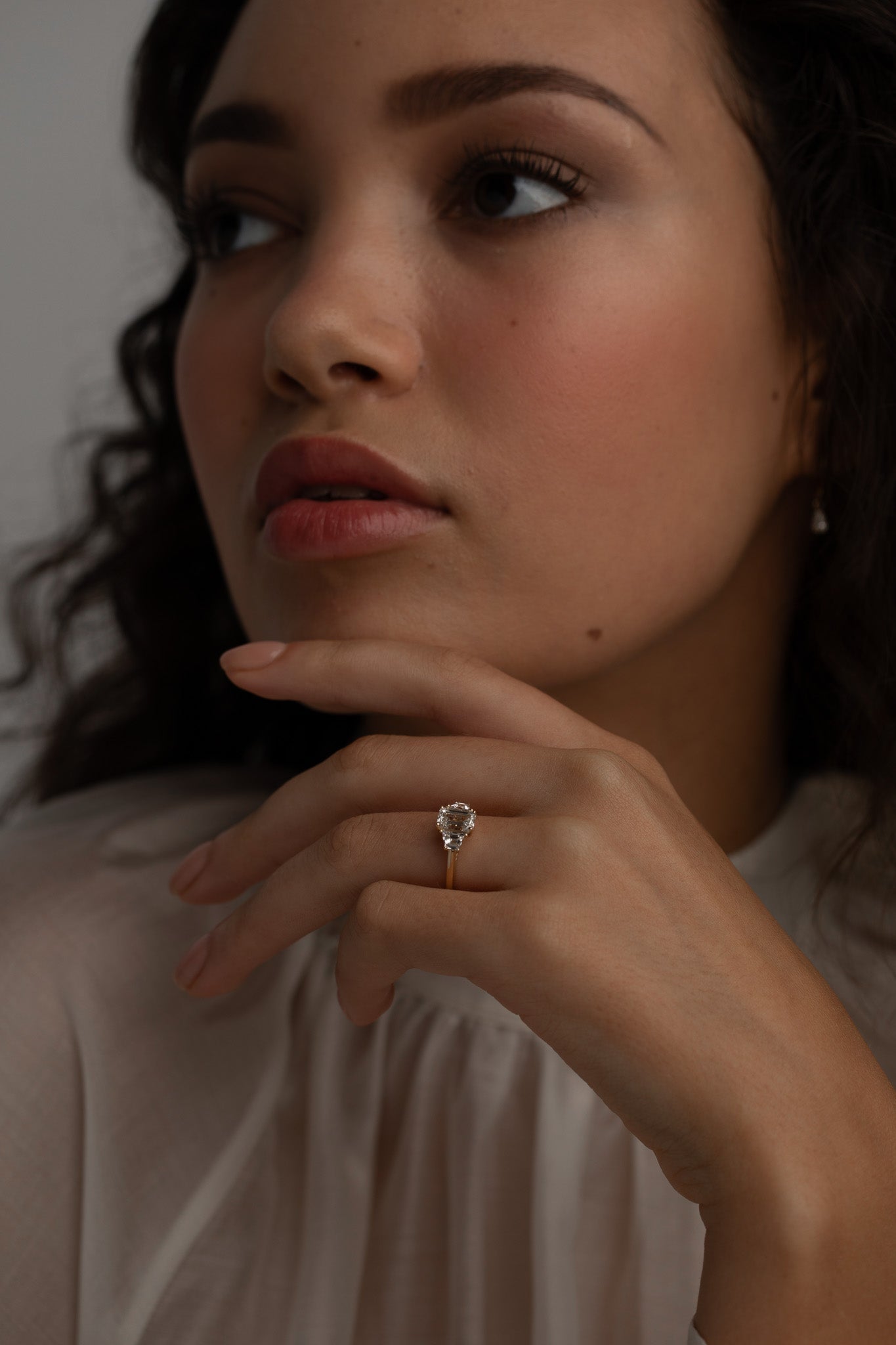 A KARAAT Emerald Trilogy ring in 18k yellow gold worn by a model, providing contemporary bridal inspiration.
