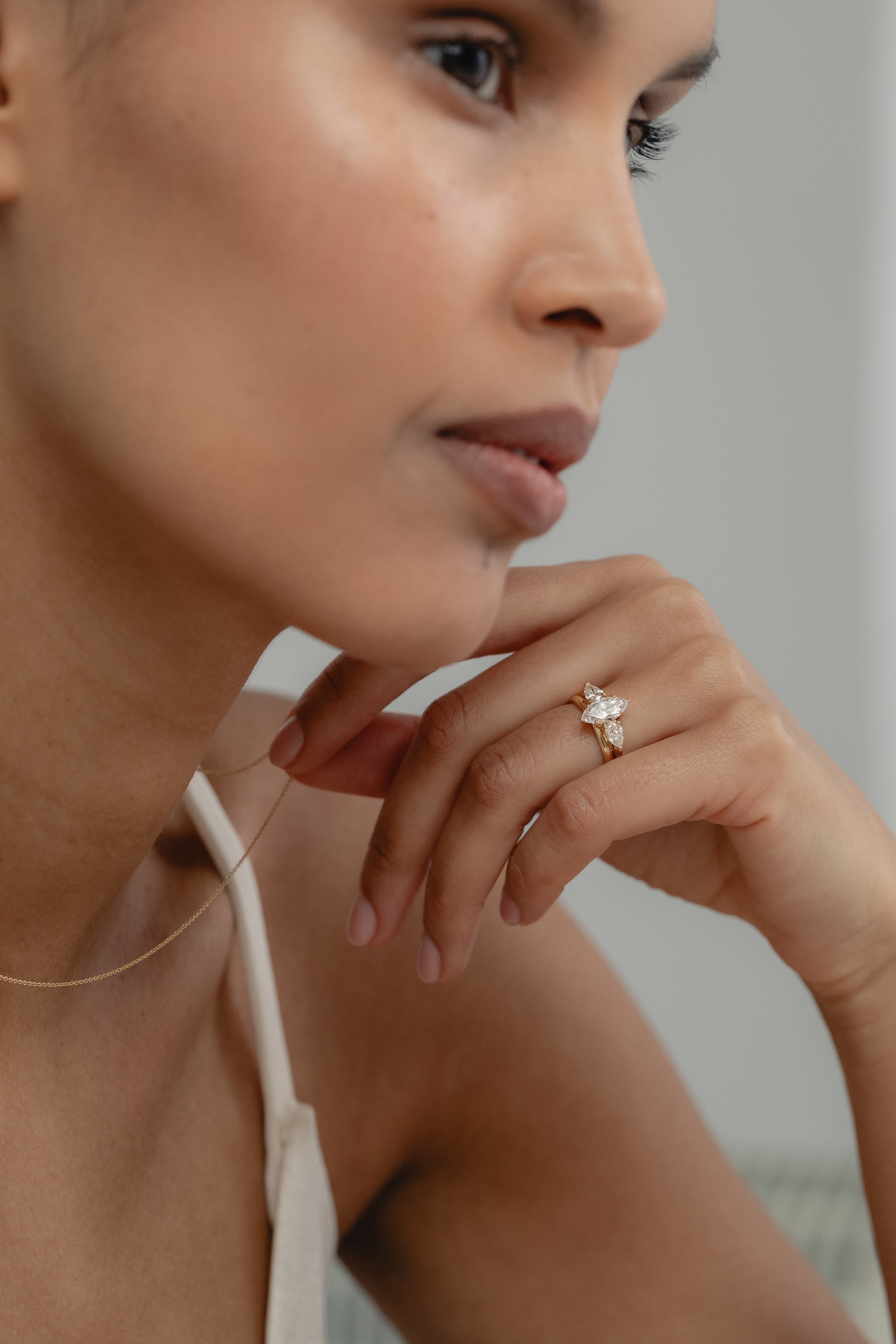 Close-up of the Marquise Trilogy three-stone lab-grown diamond engagement ring in yellow gold on a model's hand