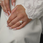 Elegant bridal lifestyle shot of a bride in a lace gown showcasing a modern bezel-set oval diamond engagement ring stacked with the Pavé Diamond Ring II in white gold.