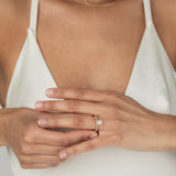 A model wearing the KARAAT Oval Six Prong Solitaire in 18k yellow gold, stacked with Marquise Half Eternity diamond wedding band.