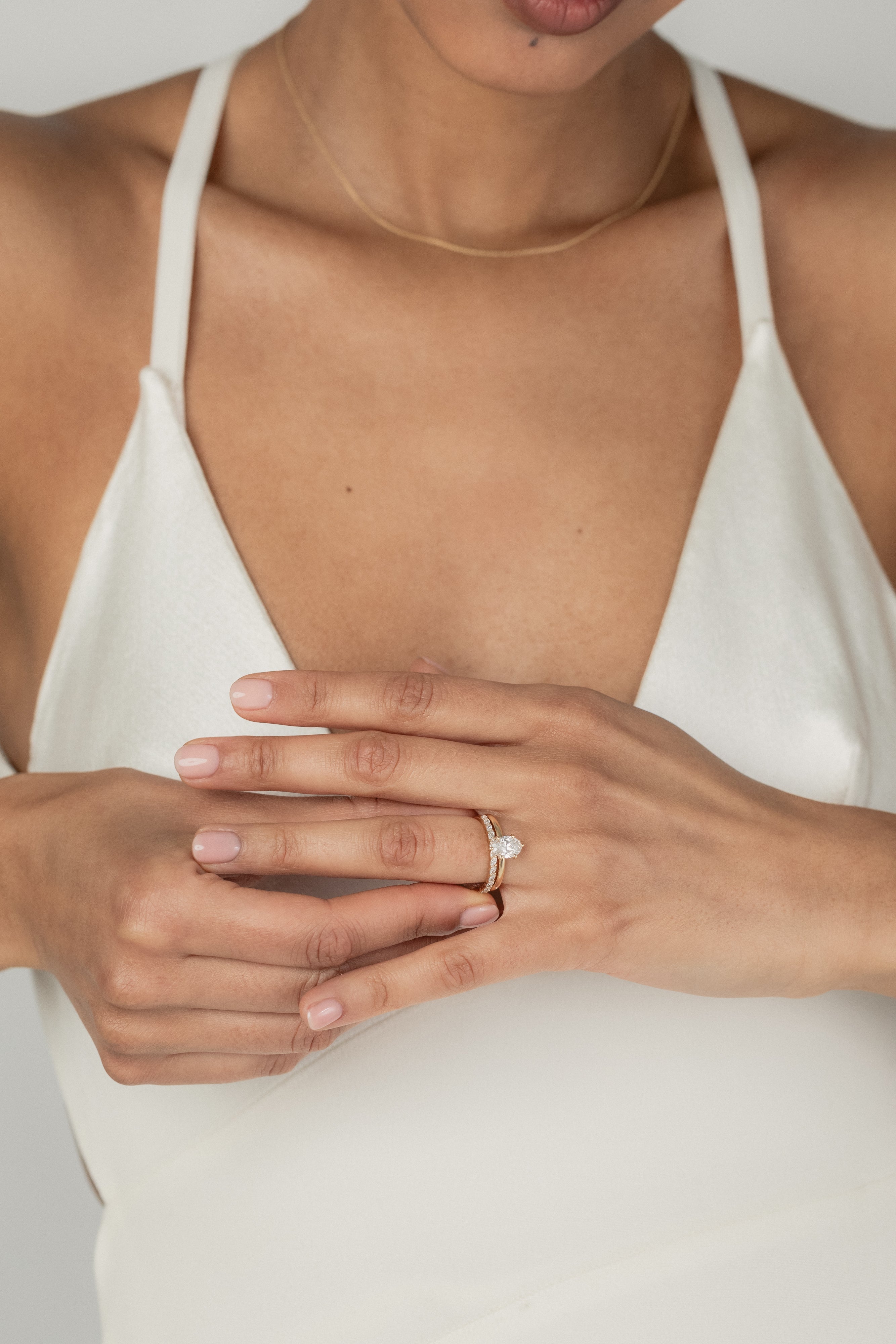 A model wearing the KARAAT Oval Six Prong Solitaire in 18k yellow gold, stacked with Marquise Half Eternity diamond wedding band.