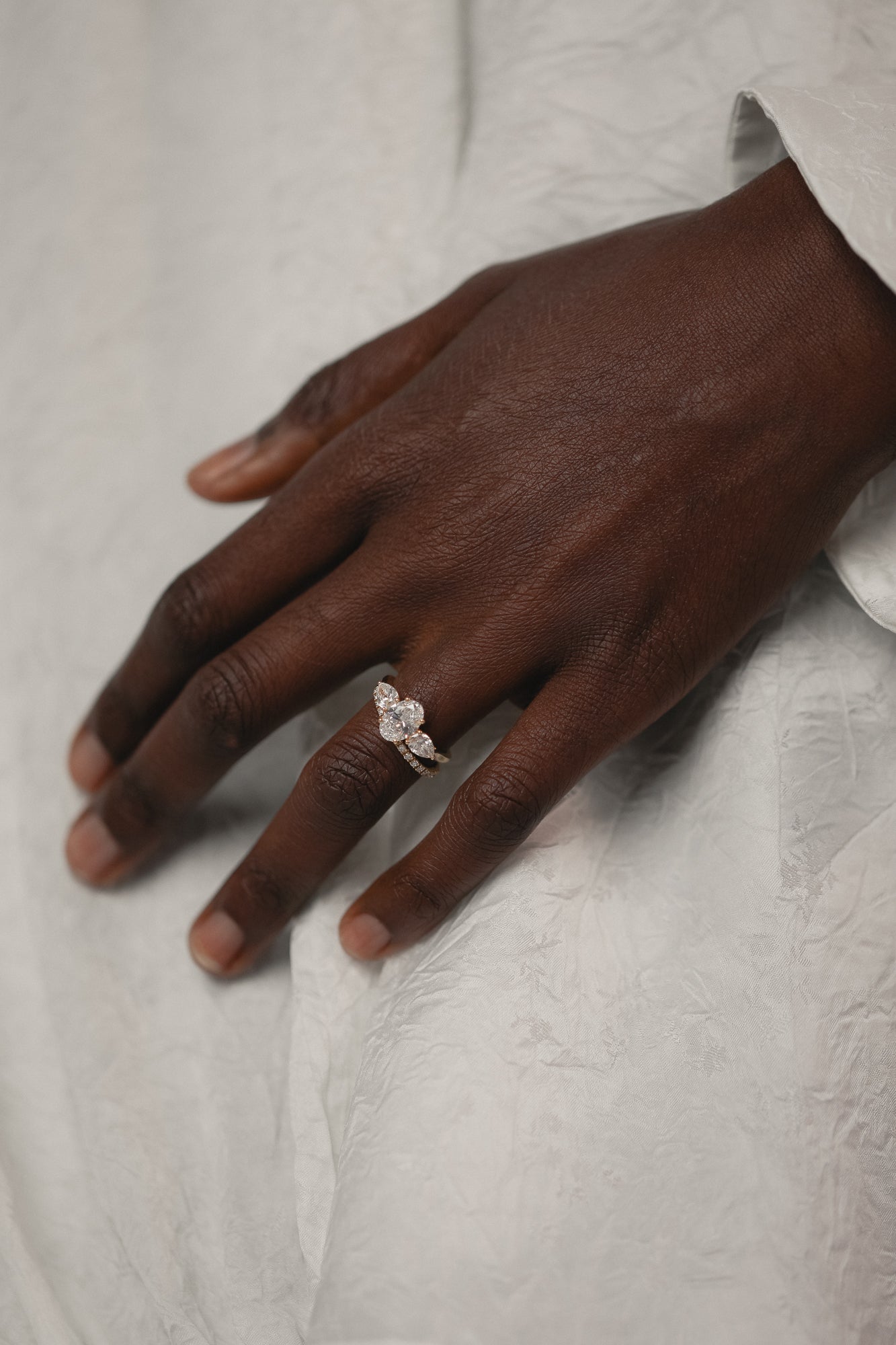 Model's hand wearing the KARAAT Oval Trilogy engagement ring in 18k yellow gold, showing the three-stone proportions.