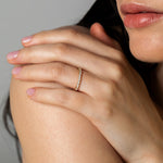 Close-up lifestyle shot of a model resting her hand on her shoulder, displaying the Pavé Diamond Ring II crafted in 18k white gold.