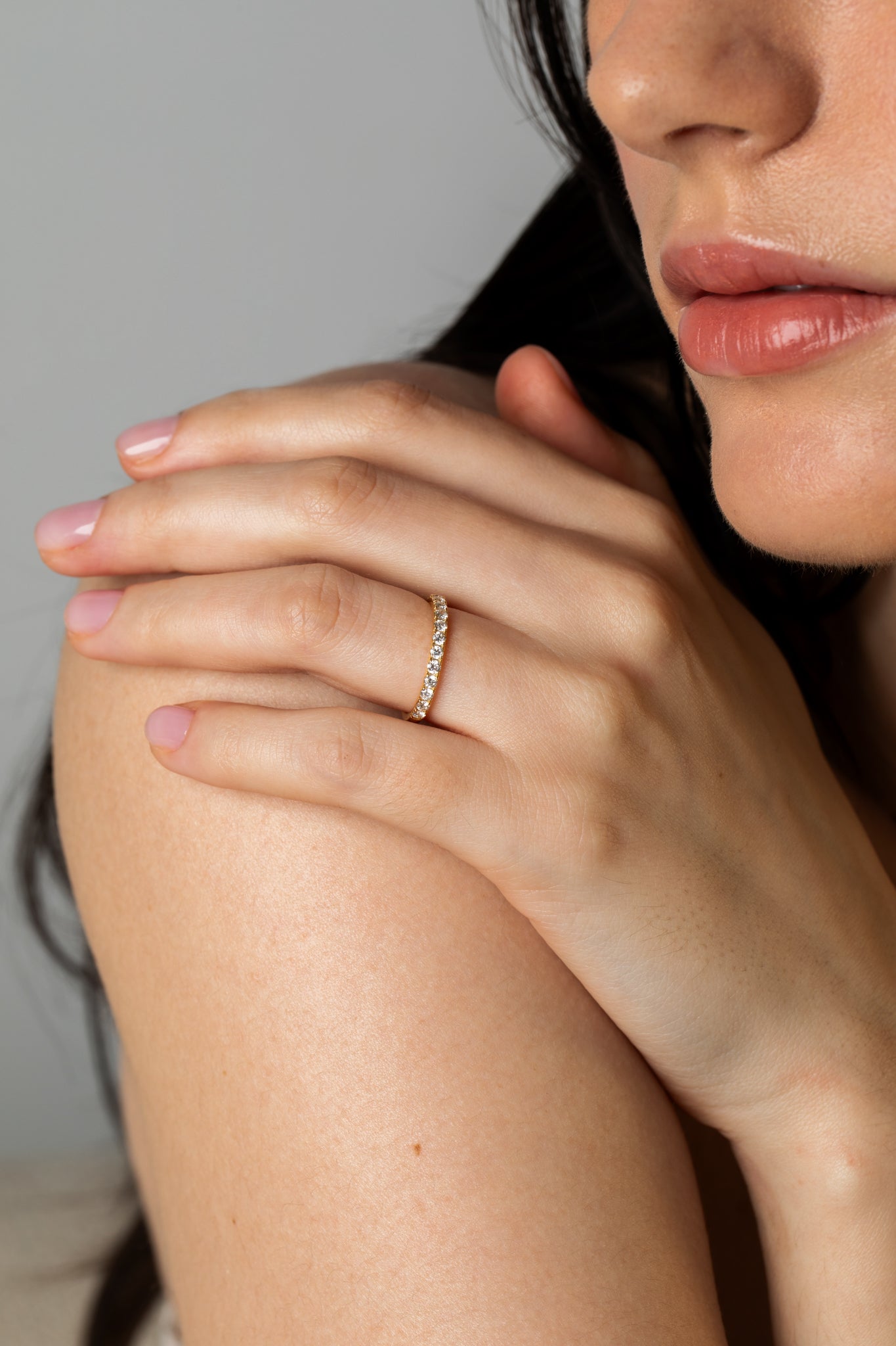 Close-up lifestyle shot of a model resting her hand on her shoulder, displaying the Pavé Diamond Ring II crafted in 18k yellow gold.