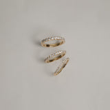 A clean flat-lay product shot displaying three KARAAT pavé diamond rings on a light grey background, showcasing different band widths and diamond carat sizes in polished yellow gold.