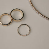 Yellow gold diamonds rings on a light gray surface with a tennis bracelet next to them.