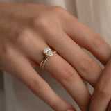 A detailed macro view of a white gold KARAAT pear-cut solitaire diamond engagement ring paired flawlessly with a sparkling pavé diamond wedding band on a model's hand.