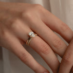 A detailed macro view of a rose gold KARAAT pear-cut solitaire diamond engagement ring paired flawlessly with a sparkling pavé diamond wedding band on a model's hand.