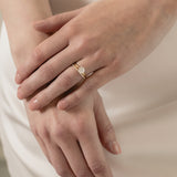 A model wearing a KARAAT Round Solitaire paired with a matching 18k white gold wedding band against a silk wedding dress.