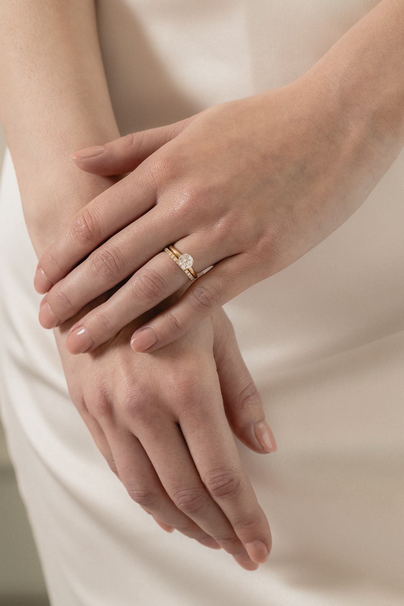 A model wearing a KARAAT Round Solitaire paired with a matching 18k white gold wedding band against a silk wedding dress.
