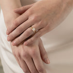 A model wearing a KARAAT Round Solitaire paired with a matching 18k yellow gold wedding band against a silk wedding dress.