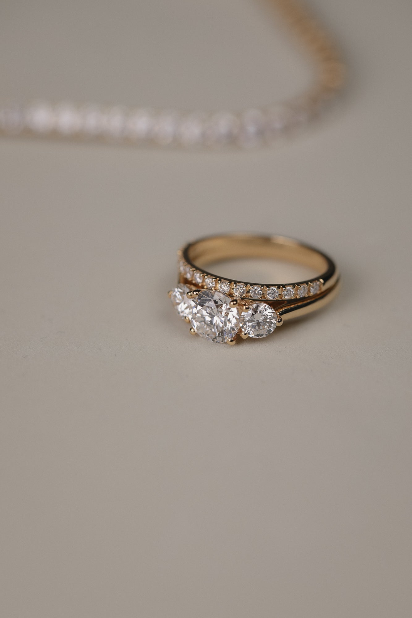 Detailed close-up of the KARAAT Round Trilogy diamond ring in 18k yellow gold, showing the three-stone setting.
