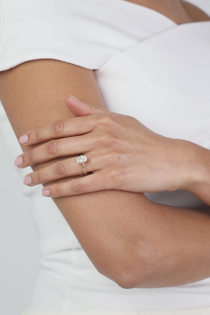 A model wearing a KARAAT lab-grown Oval Solitaire diamond ring in 18k yellow gold, showing the natural movement and sparkle of the pieces in a minimalist luxury setting.